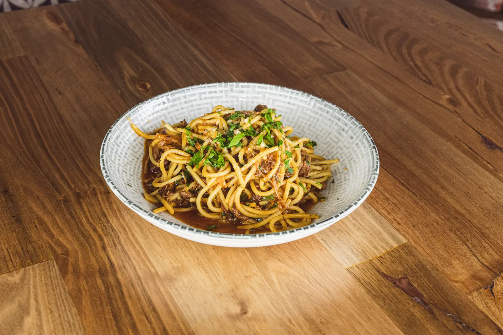 Slow-cooked brisket ragu over spaghetti in a ceramic bowl